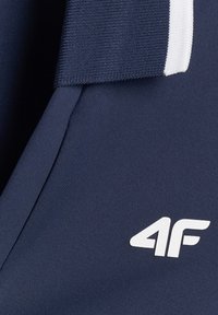 Tissu de sport bleu marine avec un logo 4F blanc et un col côtelé avec une bande blanche.