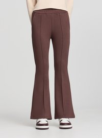 Pantaloni marroni a zampa con cintura elasticizzata, caratterizzati da cuciture laterali e una texture morbida, abbinati a sneakers bianche e bordeaux.