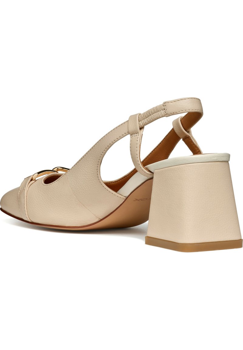 Chaussure beige en cuir à bride arrière avec design découpé, détail de boucle dorée et talon bloc épais sur fond blanc.