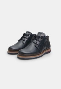 Pantofi din piele neagră, cu un design înalt, vârf rotund, talpă maro contrastantă și un accent subtil roșu pe toc. Au șireturi la partea din față.
