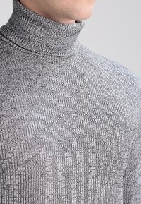 Grauer, gerippter Rollkragenpullover aus strukturiertem Strickstoff mit hohem Kragen und figurnaher Passform.