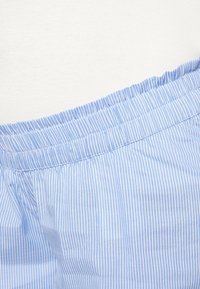 Tissu rayé bleu et blanc avec une texture douce. Comprend une taille élastique et une coupe décontractée. Mise au point sur le motif à rayures verticales.