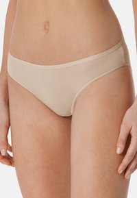 Beżowe bikini o miękkiej, prążkowanej strukturze, z niskim stanem i minimalnymi detalami szwów, podkreślające sylwetkę.