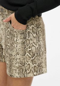 Beige shorts met een slangenprint, gemaakt van een gestructureerd materiaal, met zijzakken en een strakke pasvorm.