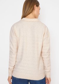 Helle beige gestrickte Pullover mit einer weichen Textur, ausgestattet mit einem gerippten Saum und Bündchen sowie einem lässigen, entspannten Design. Keine sichtbaren Muster.