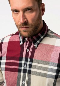 Camicia a quadri rossa e nera con accenti bianchi e grigi. Realizzata in tessuto testurizzato, presenta un colletto e bottoni visibili.