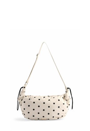 Sacoche beige à pois noirs, en matériau textile doux, avec une bandoulière réglable, des côtés froncés et une étiquette de marque discrète au bas.