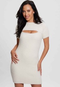 Balta vertikali megzta suknelė su trumpomis rankovėmis, turinti centrą išpjovą krūtinėje ir prigludusią siluetą, kuris baigiasi virš kelių.