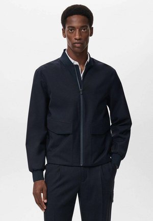Veste de bombardier marine avec col montant, fermeture éclair sur le devant et deux grandes poches à rabat ; fabriquée en un tissu lisse et structuré.