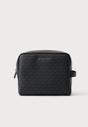 Trousse de toilette en cuir noir Michael Kors avec motif discret du logo, fermeture éclair et poignée latérale sur fond uni.