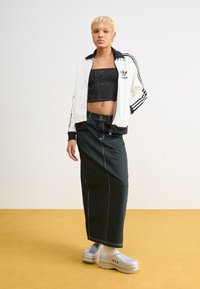 White zip-up Adidas track jacket with black accents, black cropped top, green pinstripe maxi skirt, and silver platform clogs.
