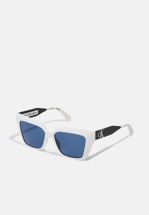 White angular sunglasses with blue lenses, featuring black tips and a logo accent on the side. Made of lightweight plastic material.