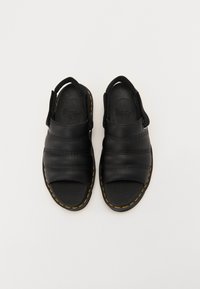 Zwarte leren sandalen met drie horizontale banden, open teenontwerp en een opvallende gele stiksels langs de zool.