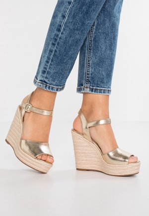 Guldmetallic kilehæle med åbent tæer, der har en spændeankelrem og en tekstureret juteholdig platformssål.