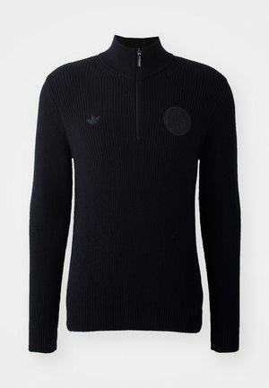 Black knitted sweater with a high collar, half-zipper, ribbed texture, and a round logo on the chest. Features long sleeves and a straight fit.