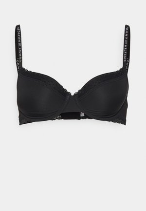 Svart bh med spetsdetaljer, formade kupor och justerbara band med en logotyp. Mjuktyg med slät yta och hak-och-öga-stängning.