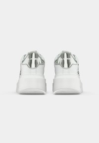 Sapatilhas brancas de plataforma com capas de calcanhar metálicas prateadas, com a marca "KARL LAGERFELD" na parte de trás, vistas de trás sobre um fundo branco.