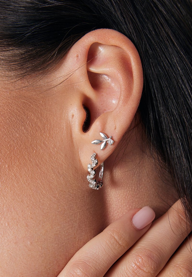 Srebrne kolczyki z motywem liścia, z małym akcentem diamentowym oraz teksturowanym kółkiem ozdobionym wieloma małymi, błyszczącymi kamieniami.