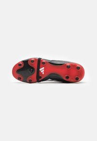 Chaussure de football avec une tige synthétique noire, une semelle extérieure en caoutchouc rouge avec des crampons circulaires, et un motif texturé pour une meilleure adhérence.