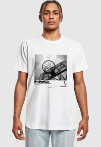 Weißes T-Shirt mit kurzen Ärmeln, das ein schwarz-weißes Grafikdesign eines Basketballkorbs und einer Stadtlandschaft zeigt, mit Textdetails am unteren Ende.