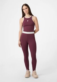 Bordowy komplet odzieży sportowej obejmujący dopasowany top na ramiączkach z białym wykończeniem oraz legginsy z wysokim stanem; gładka tkanina, minimalne oznaczenia marki.