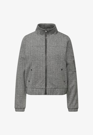 Szara marynarka w jodełkę z wysokim kołnierzem, zamkiem błyskawicznym, bocznymi kieszeniami i ściągaczami na mankietach. Charakteryzuje się luźnym krojem i teksturowaną tkaniną.