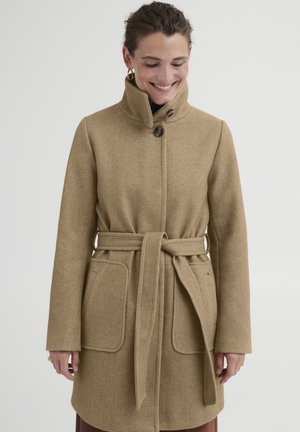 Manteau en laine beige avec un col haut, deux grandes poches avant, une ceinture nouée à la taille et une finition texturée.