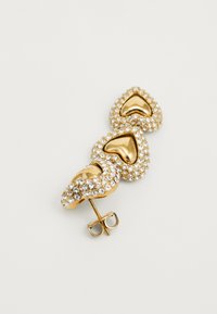 Orecchino dorato con tre design a forma di cuore; decorato con cristalli trasparenti e una superficie lucida e riflettente. Inclusa chiusura a spillo.