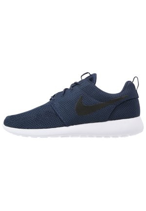 Chaussure de course Nike bleu marine avec logo swoosh noir, semelle blanche, empeigne en mesh et languette au talon pour un enfilage facile.