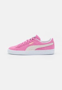 Pink Suede Sneakers mit weißen Akzenten, ausgestattet mit einer strukturierten Gummisohle, flachen Schnürsenkeln und Branding an der Seite. Klassisches Low-Top-Design.