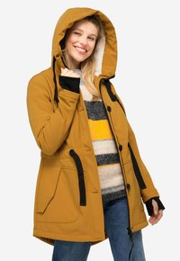 Senapsgul parkas med dragkedja fram, dragsko i huvan, svarta detaljer och två stora fickor. Fleecfodrad insidan och mjuk textur.