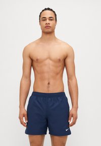 Tengerészkék fürdőnadrág elasztikus derékkal és fehér Nike logóval a bal oldalon. Simaságú anyag és laza fit. Nincsenek látható minták.