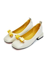 Ballerines blanches en cuir verni avec un bout carré, présentant un accent en bloc jaune et des accessoires en or. Intérieur doublé en jaune avec un petit talon.
