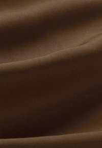 Bruine stof met een gladde textuur, voorzien van subtiele plooien en een glanzende glans. Het materiaal lijkt lichtgewicht en duurzaam te zijn.