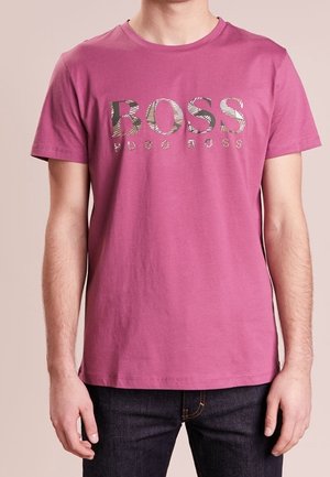 T-shirt rose clair à manches courtes, avec un logo "BOSS" audacieux et à motifs au centre. Confectionné en coton doux. Design décontracté.
