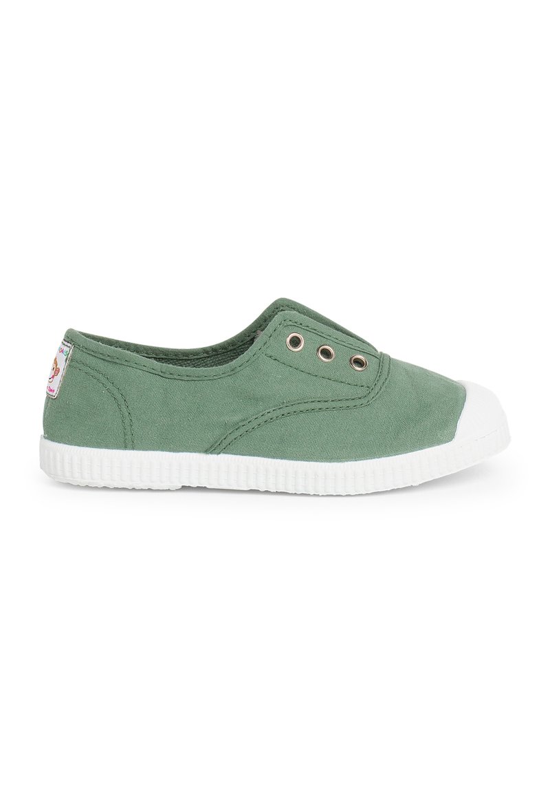 Chaussure slip-on en toile verte avec semelle en caoutchouc blanc et embout. Dispose de deux œillets en métal sur le côté pour la respirabilité.