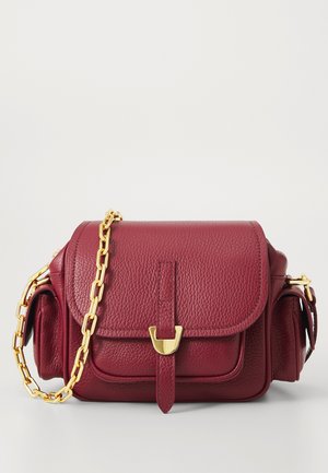 Sac bandoulière en cuir bordeaux avec une finition texturée, une bandoulière en chaîne dorée, un rabat de fermeture et un détail de boucle à l'avant. Poches latérales incluses.