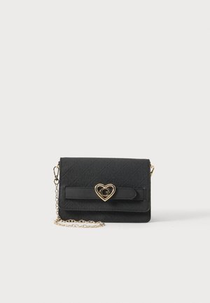 Sort quiltet crossbody taske med gyldent hjerteformet lås med et "G" og fastgjort gyldent kæderem på hvid baggrund.