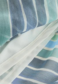 Tissu doux avec des rayures horizontales bleues, vertes et blanches, montrant un gros plan de la texture et de la couture cousue.
