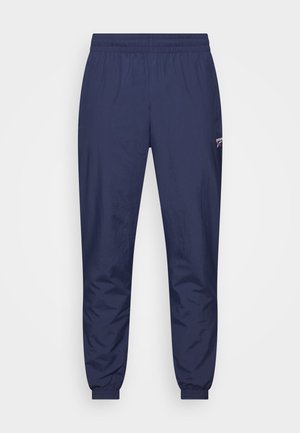 Navy track pants with elastic waistband, cuffed ankles, and subtle sheen. Features a small logo on the left thigh. Lightweight fabric.