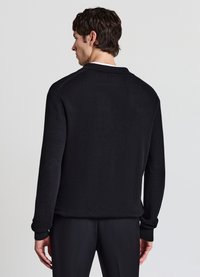 Schwarzer, gerippter Strickpullover mit langen Ärmeln und Kragen, mit einem einfarbigen, strukturierten Design und Bündchen an den Handgelenken.