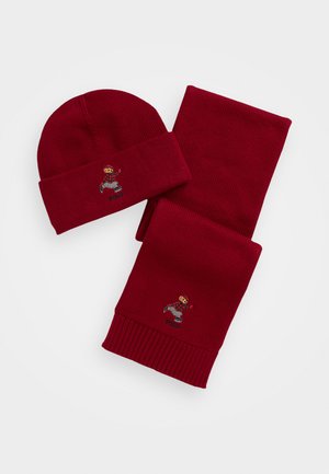 Conjunto de gorro y bufanda de punto rojo con textura acanalada. Cada pieza cuenta con un diseño de personaje bordado con la palabra "Polo."