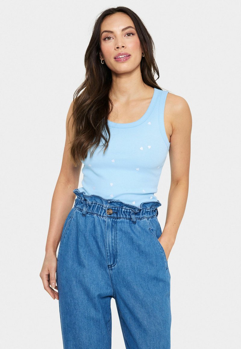 Ljusblå ribbad linne med små vita hjärtan, kombinerat med högmidjade denimbyxor med volangmidja.