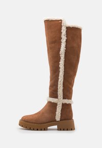 Knee-high brown suede boots with a fluffy white lining, featuring a textured sole and contrasting stitching along the seams.