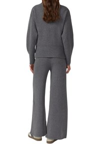 Pull en maille gris avec manches bouffantes, associé à un pantalon large en maille grise. Les deux présentent des accents côtelés. Matière texturée et confortable.