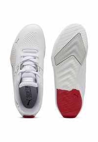 Bílé sportovní boty s perforovanými detaily, texturovanými podrážkami a červenými akcenty. Obsahují šněrování a měkké stélky pro pohodlí.