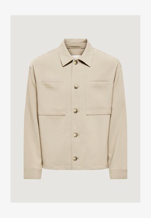 Veste beige boutonnée avec deux grandes poches poitrine, manches longues et col classique, présentée sur un fond uni.