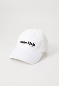 Fehér pamut baseball sapka fekete hímzett szöveggel: "calvin klein West 39th Street New York City", ívelt karimával és állítható hátsó résszel.