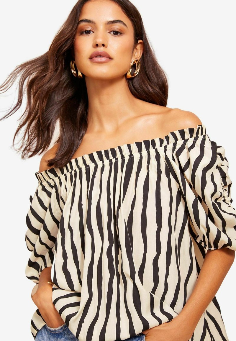 Kreemja off-the-shoulder pluus mustade vertikaalsete triipudega, puff-sleeve'ide, elastse kaelaaugu ja pehme, tekstuuriga kangaga.