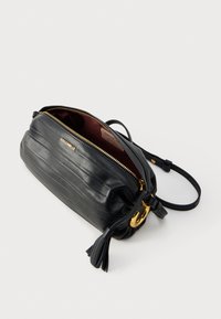 Μαύρη δερμάτινη τσάντα crossbody Coccinelle με χρυστό φερμουάρ, διακοσμητική λεπτομέρεια με φούντα και ρυθμιζόμενο λουρί, εμφανίζεται μερικώς ανοιχτή σε λευκό φόντο.